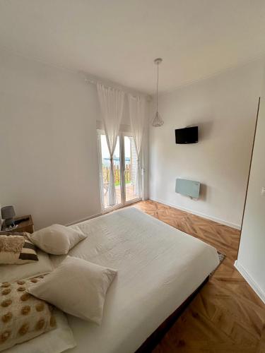 a large bed in a white room with a window at Apartamentos LAMAROSA -LAS PLAYAS in Burela de Cabo
