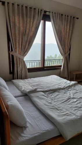 a bed in a bedroom with a large window at HK Heights - Sunset Valley Retreat in Nathia Gali