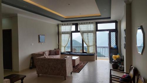 a living room with a couch and large windows at HK Heights - Sunset Valley Retreat in Nathia Gali