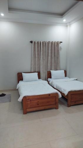 two twin beds in a room with a window at HK Heights - Sunset Valley Retreat in Nathia Gali
