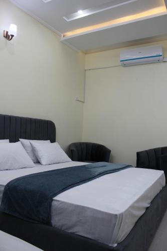 a bedroom with a large bed and two chairs at Islamabad Elite Suites in Islamabad
