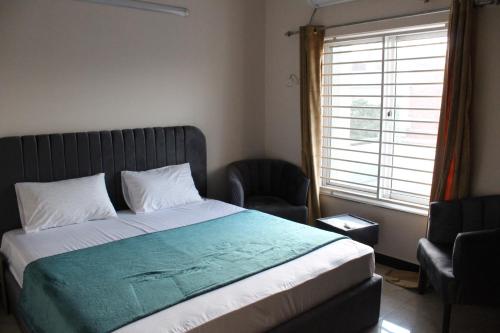 a bedroom with a bed and a chair and a window at Islamabad Elite Suites in Islamabad