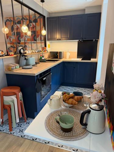 une cuisine avec des armoires bleues et une table avec de la nourriture dans l'établissement Maison Sorbier - Appartement 2, à Nevers
