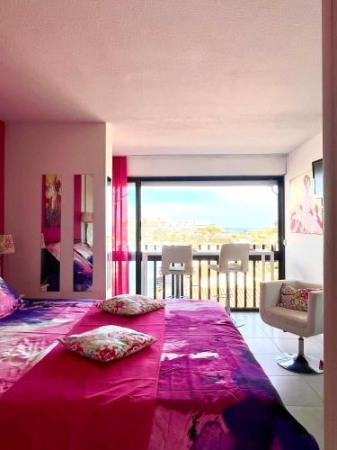 - une chambre avec un grand lit violet et un balcon dans l'établissement Absolu chic naturiste, au Cap d'Agde