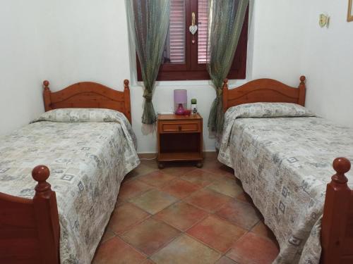 a bedroom with two beds and a night stand at Mar y Sol San Teodoro Lu Fraili in Nuragheddu