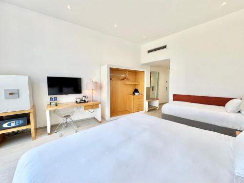 a bedroom with a bed and a desk and a tv at Hilton Sorrento Palace in Sorrento