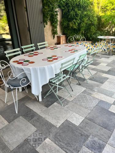 une table blanche et des chaises sur une terrasse dans l'établissement Maison avec piscine en Drome provençale, à Saint-Maurice-sur-Eygues
