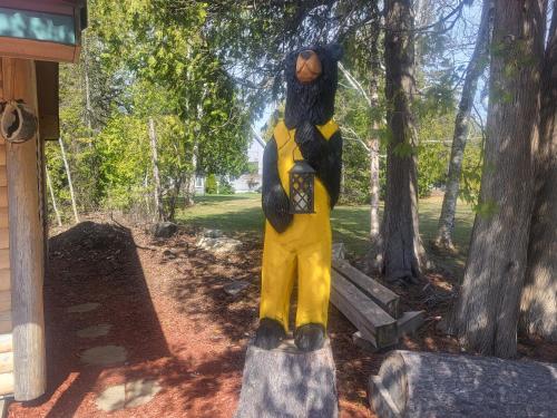 a statue of a person dressed in yellow standing on a tree stump at Moosewood Inn in Saint Ignace