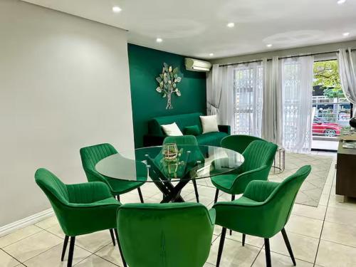 ダーバンにあるThe Green Diamond - Stylish and Spacious Umhlanga Ridge Apartment - Rooftop Pool and King Bedsのダイニングルーム(ガラステーブル、緑の椅子付)