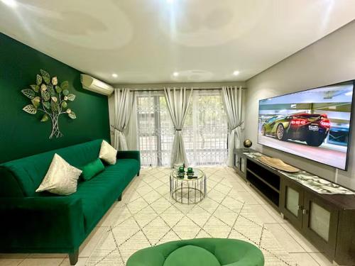 ダーバンにあるThe Green Diamond - Stylish and Spacious Umhlanga Ridge Apartment - Rooftop Pool and King Bedsのリビングルーム(緑のソファ、薄型テレビ付)