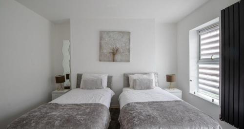 two beds in a room with white walls at Business & Family-Friendly 2BR Racecourse Park 5min to Town & Hospital Parking WiFi in Kingsthorpe