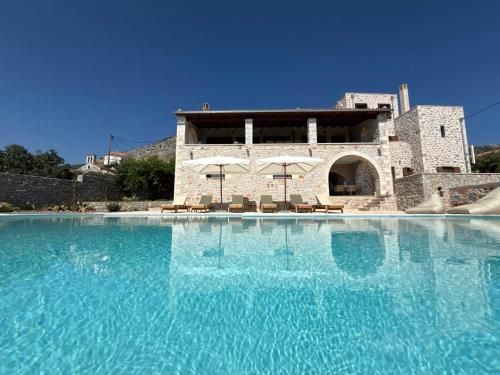 a large pool of blue water in front of a building at Pirgos Petropoulea in Poliána