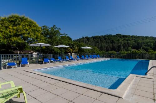 une grande piscine avec des chaises et des parasols bleus dans l'établissement Cottage 6 personnes climatisé, à Saint-Martial-de-Nabirat