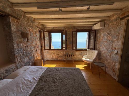 a bedroom with a bed and a chair and windows at Pirgos Petropoulea in Poliána