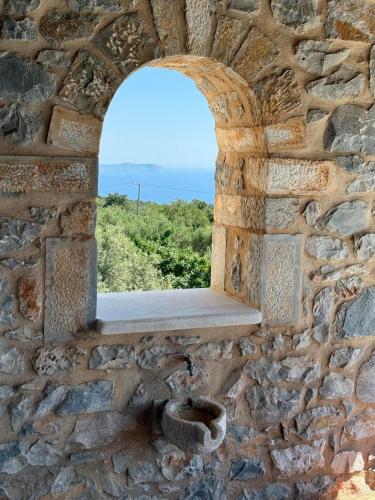 a window in a stone wall with a bench at Pirgos Petropoulea in Poliána