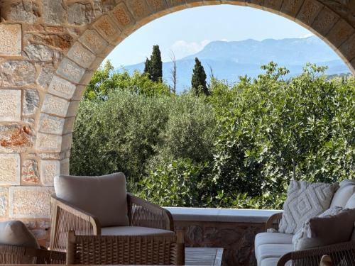 an arch in a stone wall with chairs and trees at Pirgos Petropoulea in Poliána