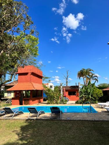 a swimming pool with chairs and a house at Pousada Villa Luna in Penedo