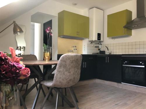 a kitchen with green cabinets and a wooden table and chairs at appartement cosy in Saint-James