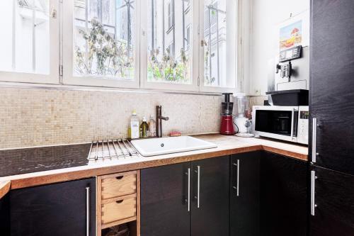 une cuisine avec un évier et un micro-ondes dans l'établissement Paul Escudier - Spacieux et lumineux appartement au cœur de Paris, à Paris