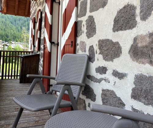 two chairs sitting on a porch with a stone wall at Castel Madonna in San Martino di Castrozza