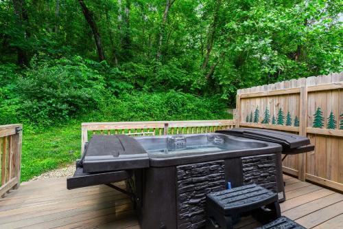 a hot tub on a deck with a fence at Grey Pines at Hocking Vacations in Logan