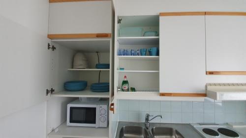 a kitchen with white cabinets and a sink and a microwave at Vanha-Merivartioasema in Kotka
