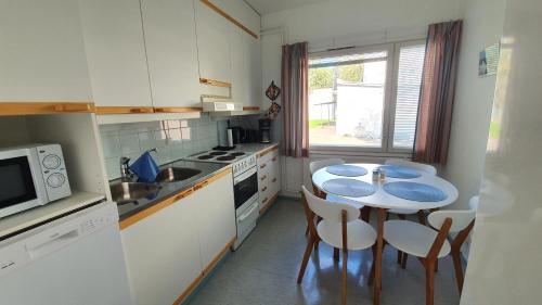 a kitchen with a table and chairs and a microwave at Vanha-Merivartioasema in Kotka