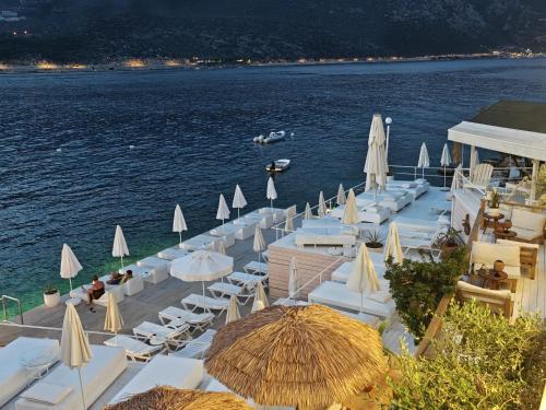 a bunch of tables and chairs with umbrellas on the water at Club Çapa Hotel in Kas