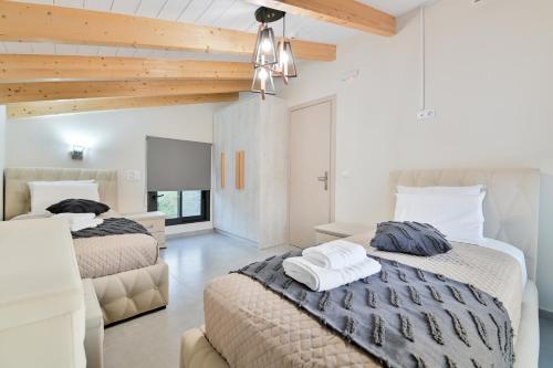 two beds in a bedroom with white walls and wooden ceilings at September15 Suites- Meganisi in Meganisi