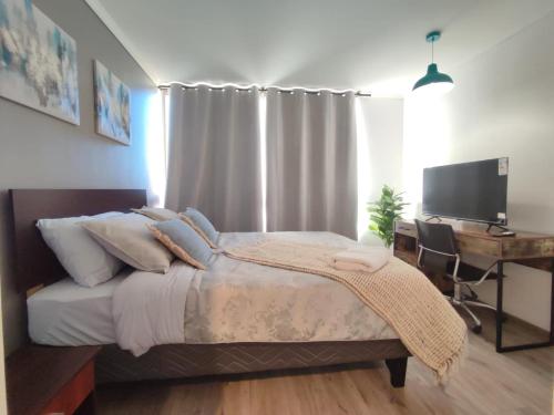 a bedroom with a bed and a desk with a computer at Departamento Ejecutivo - central en Calama in Calama