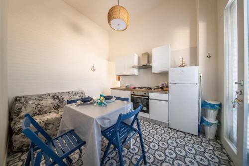 a kitchen with a table and blue chairs in a room at The twins Rooms in Marettimo 2 in Marettimo