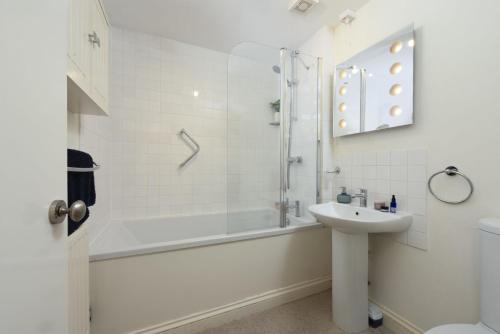 ein weißes Badezimmer mit Waschbecken und Dusche in der Unterkunft Bessie Ellens Cottage in Fowey