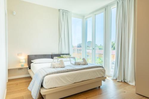 a white bedroom with a bed and large windows at Light Garden-Luxury apartment with private parking in Monza