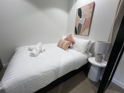 a bedroom with a bed with white sheets and pillows at River Glow at Queens Wharf Level 43 in Brisbane