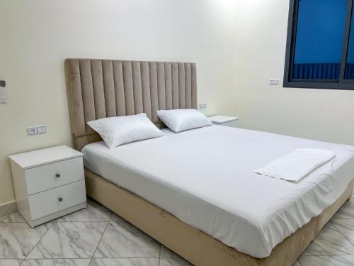 a bedroom with a large white bed and a nightstand at Appartement Alhoceima in Imejoudene