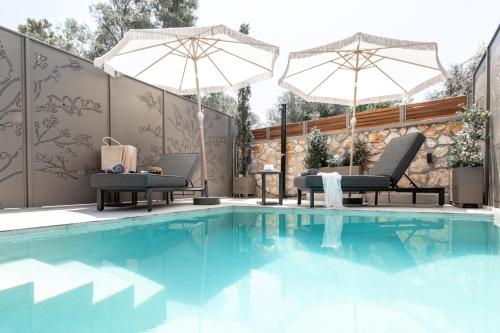 a swimming pool with two umbrellas and two chairs at September15 Suites- Meganisi in Meganisi