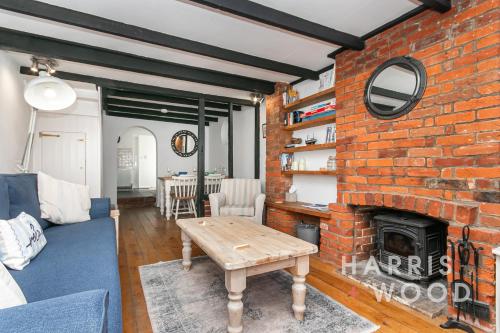 a living room with a brick fireplace and a blue couch at Saltmarsh Cottage in Brightlingsea