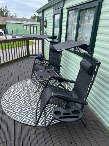 two chairs sitting on the deck of a house at West Lakes Affordable Caravan in Lamplugh