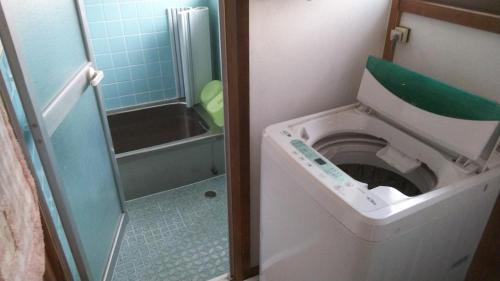 a small bathroom with a toilet and a shower at 幕山ハウス in Yugawara