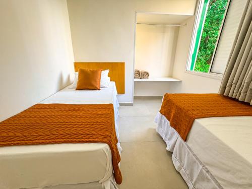 a bedroom with two beds with orange and white sheets at Hotel Nacional Inn Guarujá in Guarujá