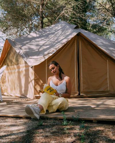 a woman sitting in a tent reading a book at Camping Santa Elena in Lloret de Mar
