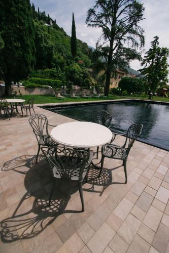 a white table and chairs next to a pool at Ventus Park Hotel in Nago-Torbole