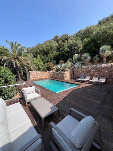 - une piscine avec des chaises longues et des chaises sur une terrasse en bois dans l'établissement Torraccia, à Porto-Vecchio