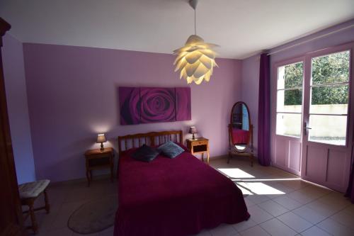 a bedroom with purple walls and a bed and a chandelier at Ancien presbytère restauré - Gites de France 3 épis in Parranquet