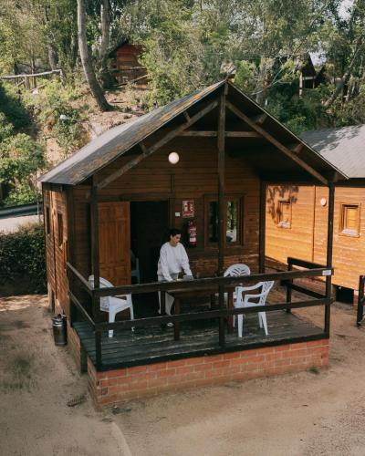a man standing in the doorway of a log cabin at Camping Santa Elena in Lloret de Mar