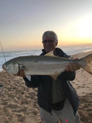 a man holding a fish on the beach at Plett-Dunes 41 in Keurboomstrand