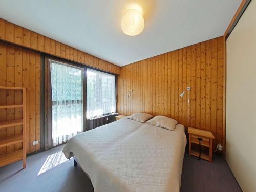 a bedroom with a bed in a room with wooden walls at Appartement au centre - 3 pièces, 6 personnes, ascenseur - FR-1-241-222 in Le Grand-Bornand