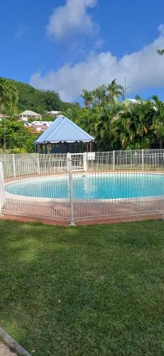 a fence around a swimming pool with a gazebo at Studios Becassine et Tangara Domaine de Belfond St Anne in Sainte-Anne