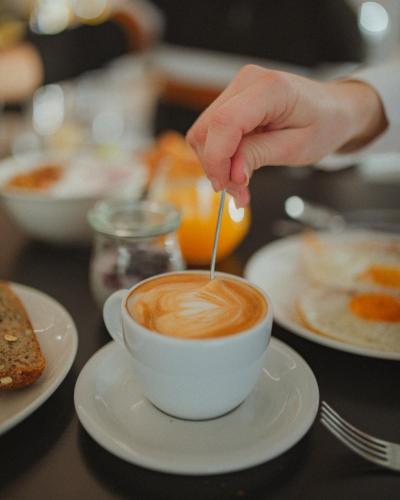a person stirring a cup of coffee with a spoon at Hotel Capris Capodistria Boutique in Koper