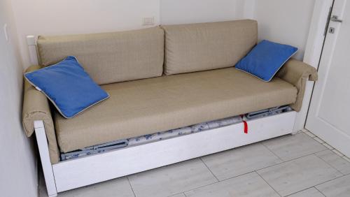 a couch with two blue pillows on it at Rooms Apartaments Santa Teresa in Capo Testa